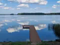 Drewniane molo prowadzi do spokojnego jeziora nisko, gdzie błękitne niebo z białymi chmurami odbija się w tafli wody.