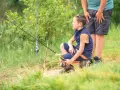 Chłopiec z wędką czeka na branie, przypominając sobie o okresie ochronnym ryb. Tabela z gatunkami ryb i terminami jest ważna dla każdego wędkarza.