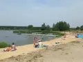 Słoneczny dzień nad zalewem Murowaniec. Ludzie kąpią się, opalają na plaży i odpoczywają.