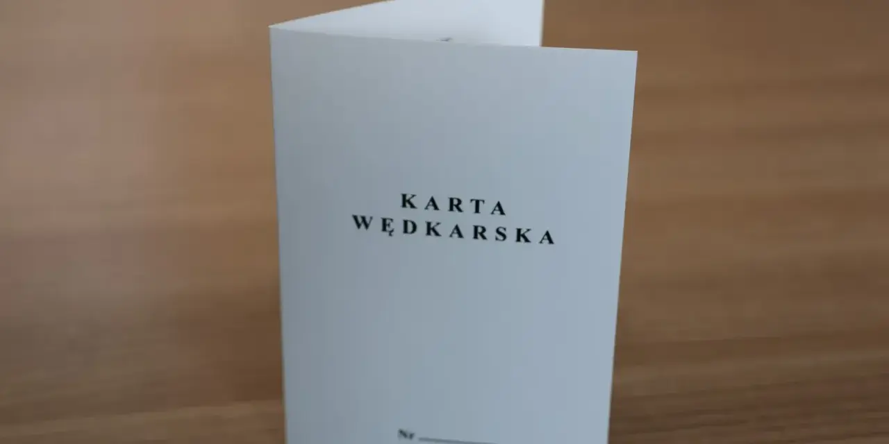 Oto jak wygląda karta wędkarska: biała, złożona kartka z napisem "KARTA WĘDKARSKA" i miejscem na numer.