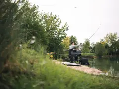 Wędkarz przy brzegu, łowiący ryby. Pokazano, jak założyć dzwonek na wędkę, by usłyszeć branie.