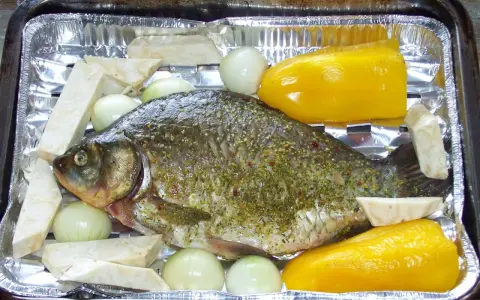 Karp przyprawiony, gotowy do pieczenia z cebulą, selerem i papryką. Idealny przepis, jak przyrządzić karasia.