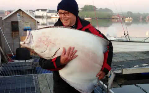 Szczęśliwy wędkarz z ogromnym halibutem. Zapach halibut na jakie ryby? Ten gigant to dowód, że warto łowić!