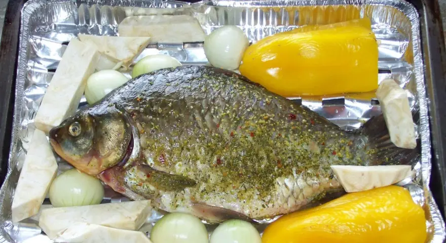 Karp przyprawiony, gotowy do pieczenia z cebulą, selerem i papryką. Idealny przepis, jak przyrządzić karasia.