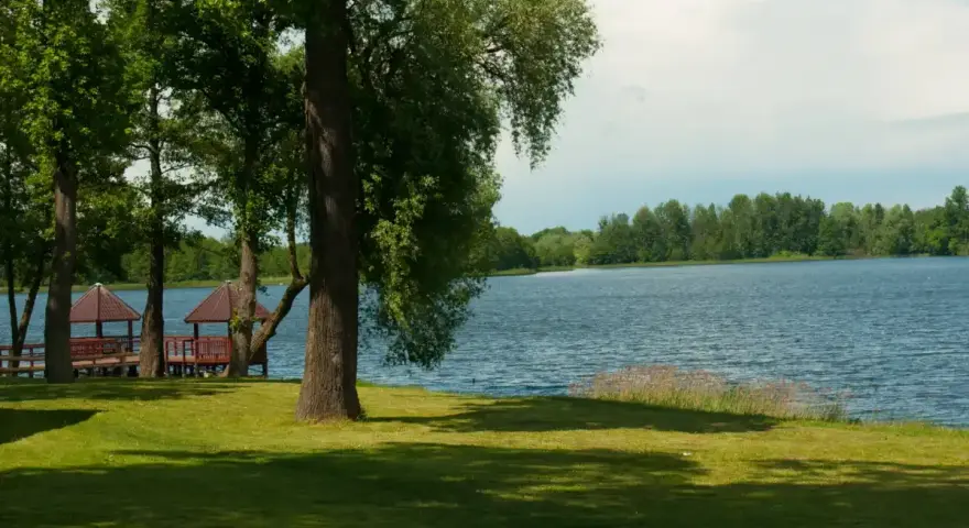 Malownicze jezioro Szczutowskie z altanami na brzegu, otoczone zielenią.