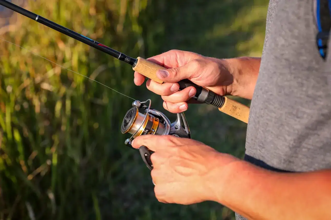 Dłonie trzymające wędkę i kołowrotek, gotowe do łowienia ryb. Czas na street fishing!