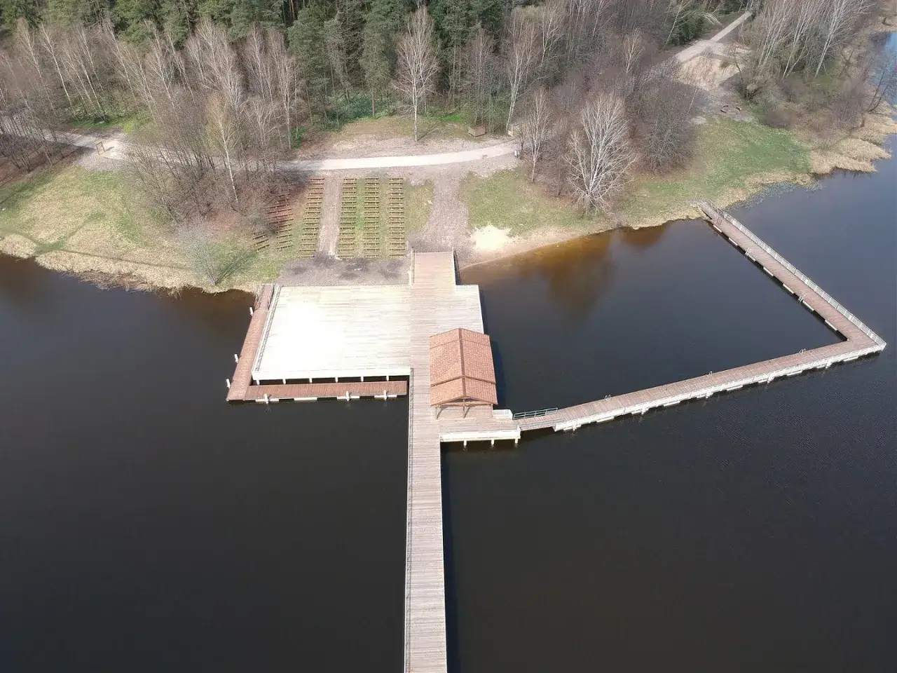 Drewniane molo i pomosty nad wodą, z rzędami ławek na brzegu. Idealne miejsce na wypoczynek nad zalewem Czarna Białostocka.